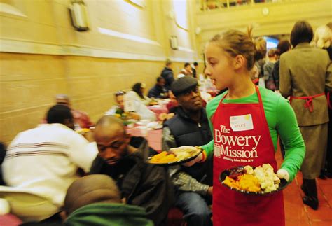 a woman in an apron holding plates of food while standing next to a group of people