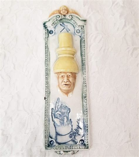 a ceramic wall hanging with an image of a cat wearing a hat on it's head