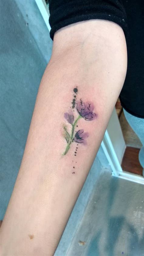 Watercolor style purple flower on the forearm.