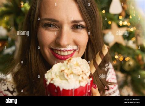 Christmas time. Portrait of happy elegant 40 years old woman with festive hot chocolate cocktail ...