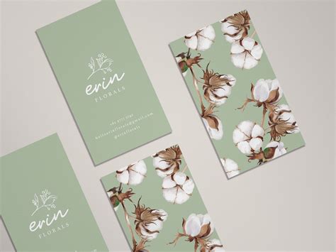 three business cards with white flowers on green and brown paper, one has the word enn printed on it