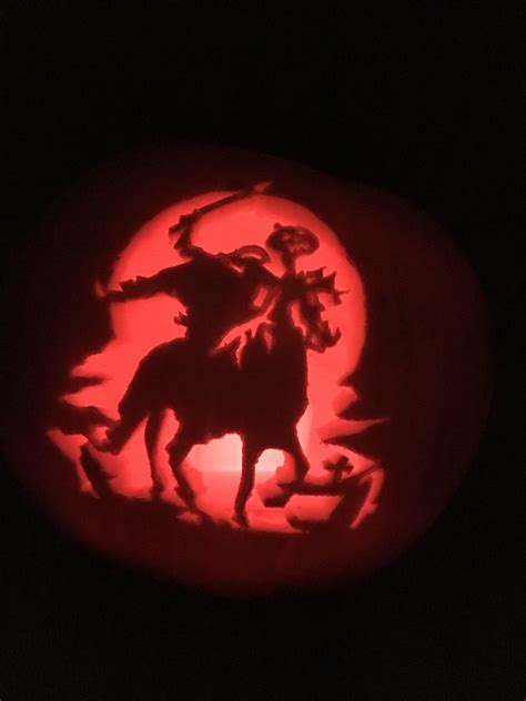 a carved pumpkin with a silhouette of a man on a horse in front of a full moon