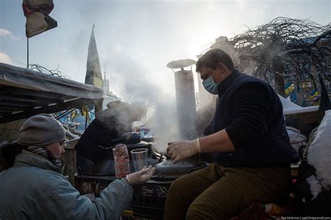 two people are cooking food outside in the snow while wearing facemasks and gloves