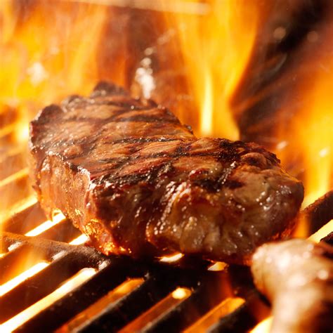 beef steak on the grill with flames. - The Butcher Shop, Inc.