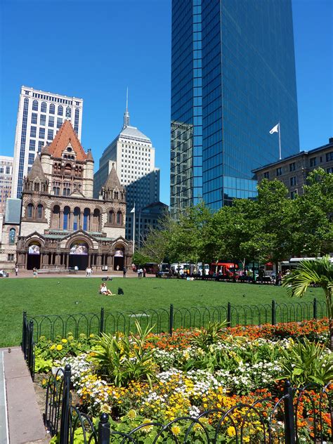 a city park with lots of flowers in the foreground and tall buildings in the background