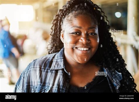 Portrait of young african farmer woman working inside cowshed - Focus ...