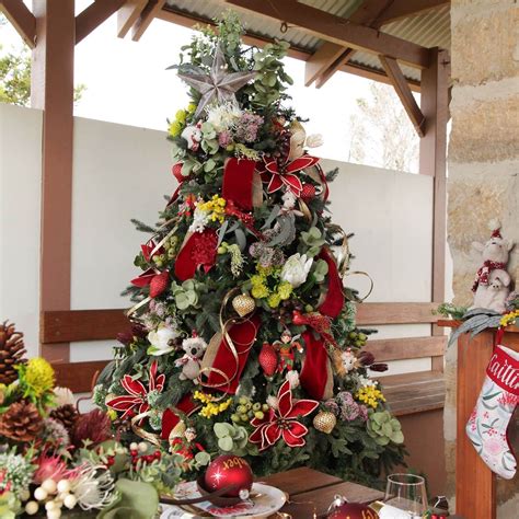 a christmas tree decorated with red ribbons and flowers