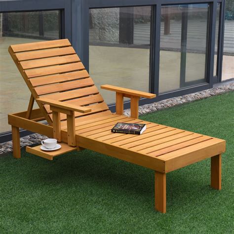 a wooden chaise lounge chair sitting on top of green grass