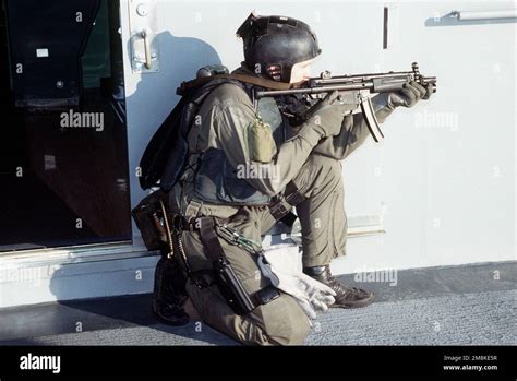 A U.S. Navy SEAL, in firing position armed with an MP5-N sub-machine gun, sets up a security ...