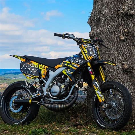 a yellow and black dirt bike parked next to a tree