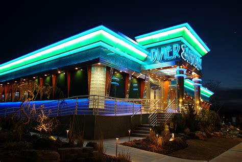 a building that is lit up at night with neon lights on the front and side