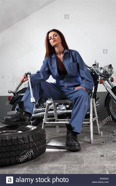 Download this stock image: Photo of a beautiful female mechanic working on a motorcycle wearing ...