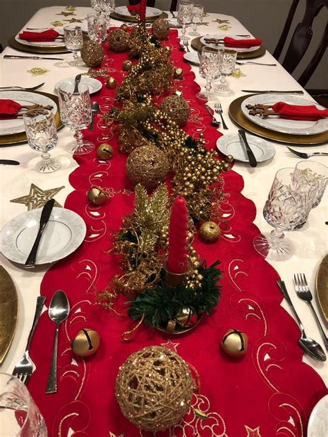 the table is set for christmas dinner with red and gold placemats, silverware, and ornaments