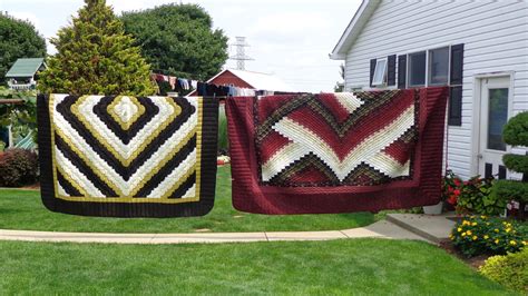 two quilts hanging on a clothes line in front of a house with green grass