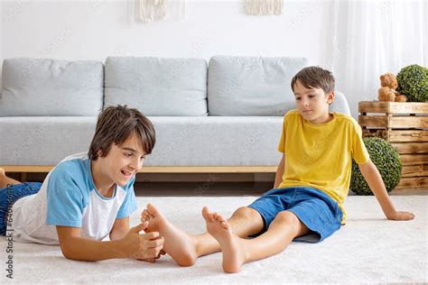 Happy positive children, tickling on the feet, having fun together, boy brothers at home having ...