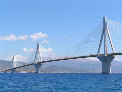 a large bridge spanning over the ocean with mountains in the background