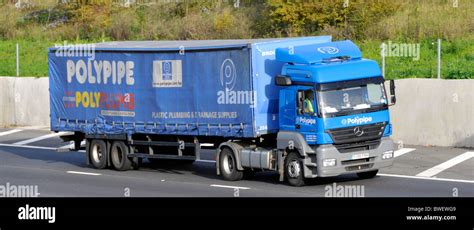 Side & front of blue Polypipe Mercedes supply chain delivery lorry truck driver & articulated ...