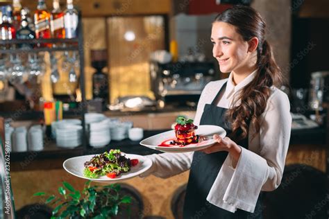 Waiter serving in motion on duty in restaurant. The waiter carries dishes Stock Photo | Adobe Stock