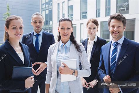 Portrait of confident business people standing outside office building — profession, Business ...