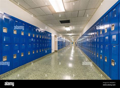 Typical, nondescript USA empty school hallway with blue metal lockers ...