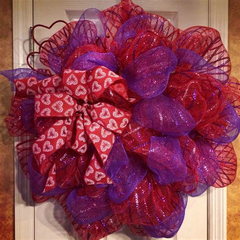 a red and purple mesh wreath with hearts on the front door, attached to ...