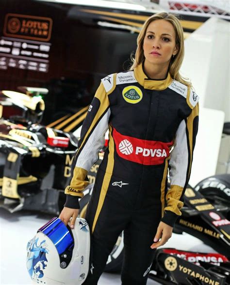 a woman in a racing suit holding a helmet