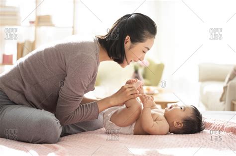 Young Chinese mom taking care of baby girl stock photo - OFFSET