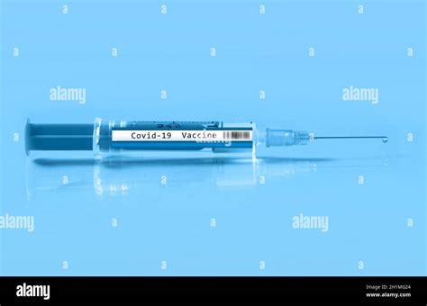 Close up of a syringe labeled Covid 19 vaccine on a light blue background Stock Photo - Alamy