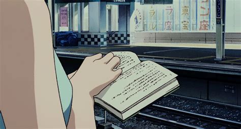 a person holding a book in front of a train station