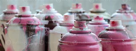 A lot of dirty and used aerosol cans of bright pink paint. Macro photograph with shallow depth ...