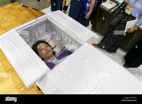 Visitors look at a member of staff inside a coffin after concluding a ...