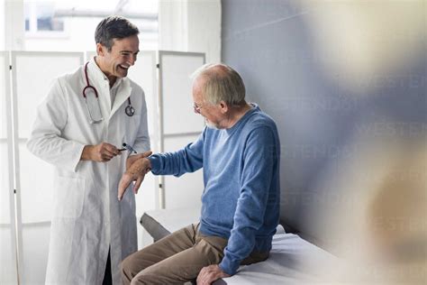 Happy doctor examining senior patient in medical practice stock photo