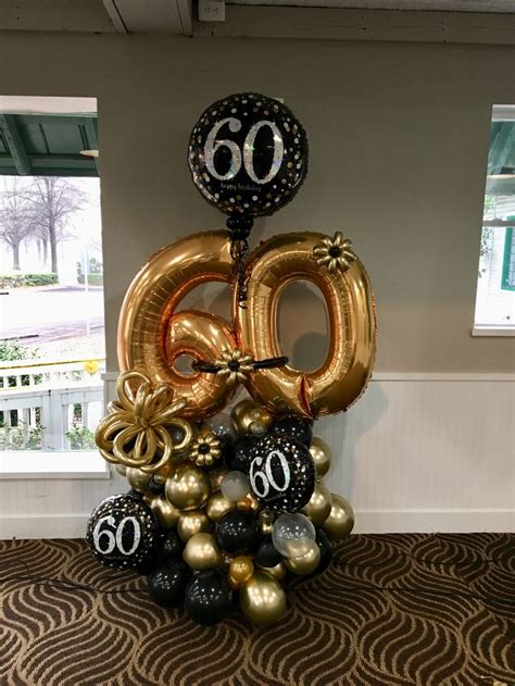 the number 60 balloon is on top of some black and gold balloons