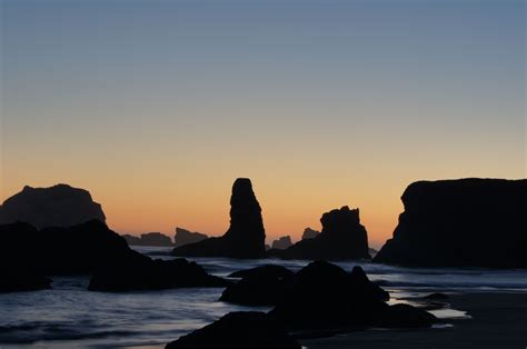 the sun is setting over some rocks on the beach