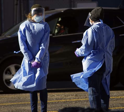 Two medical staffers brave strong winds while working at a drive-up COVID-19 testing site at ...