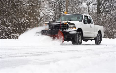 Man in pickup truck plowing road during snow storm - Risingers Landscaping