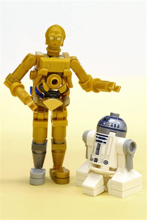 a toy robot standing next to a lego star wars r2d2 droid