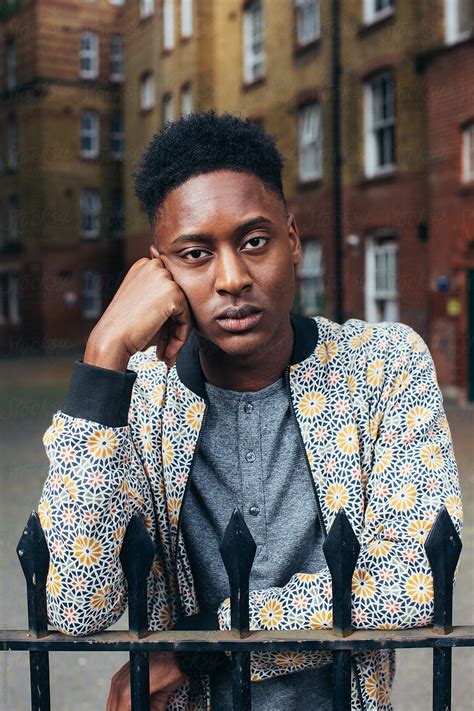 "Young Cool Black Man Standing Behind Iron Fence" by Stocksy Contributor "VISUALSPECTRUM" - Stocksy