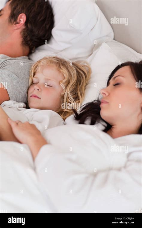 Portrait of a boy sleeping between his parents Stock Photo - Alamy