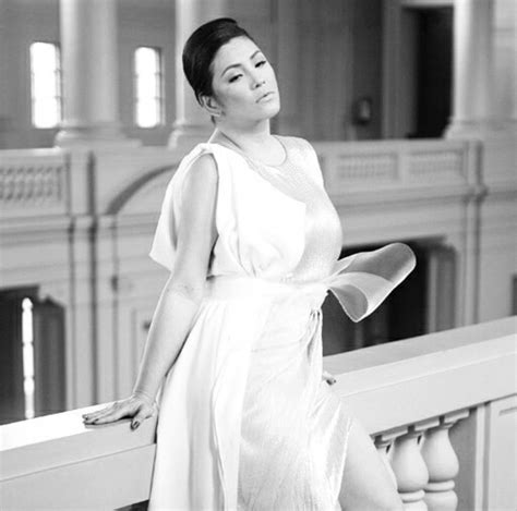 black and white photo of woman in dress standing on balcony railing ...