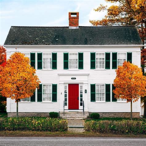 an old white house with red door and black shutters on the front ...