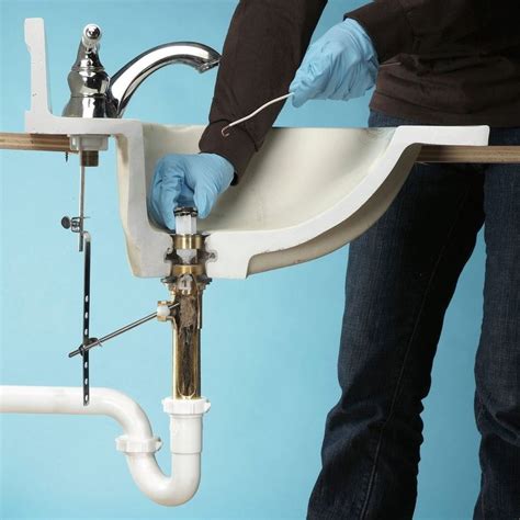 a person in blue gloves fixing a sink faucet