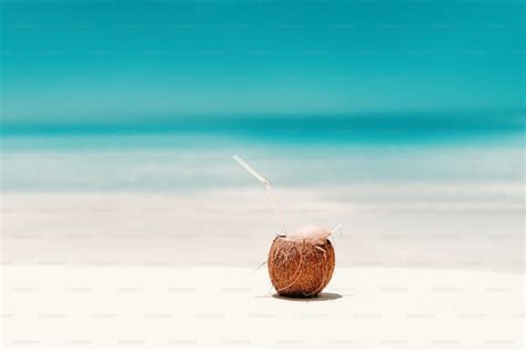 Picture of cocktail in coconut on the beach. In background ocean. photo ...