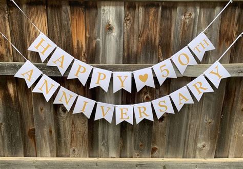 a happy 50th anniversary banner hanging from a wooden fence with the ...