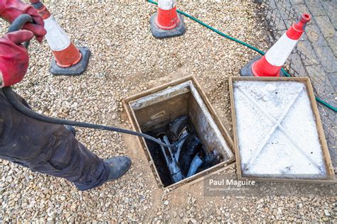 Stock photo - Man unblocking sewage drain through open inspection ...