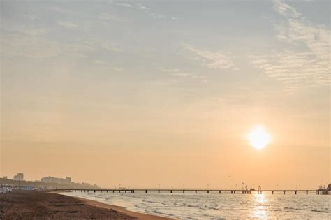 Premium Photo | Sunset over sandy beach and sea pier and building silhouettes