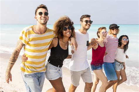 Group of friends walking on the beach stock photo