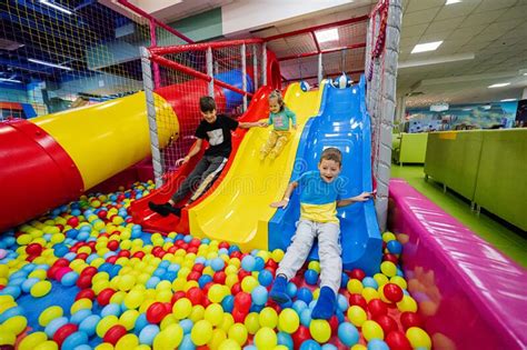 Happy Kids Playing at Indoor Play Center Playground. Children Slides in Colored Slide into Balls ...