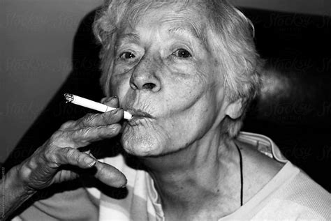 "Elderly Woman Smoking A Cigarette" by Stocksy Contributor "Chelsea Victoria" - Stocksy