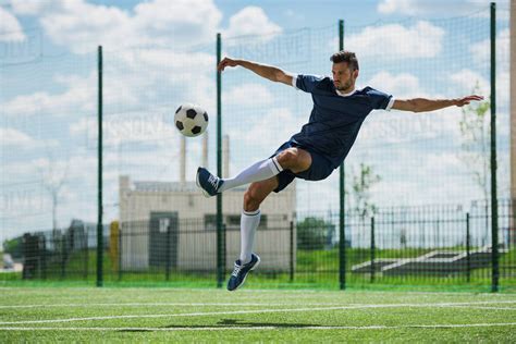 Athletic soccer player kicking ball on soccer pitch - Stock Photo ...